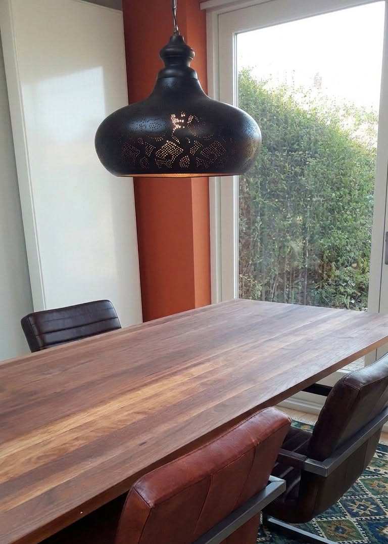 donker mangohout afwerking van hanglamp boven donkere eettafel